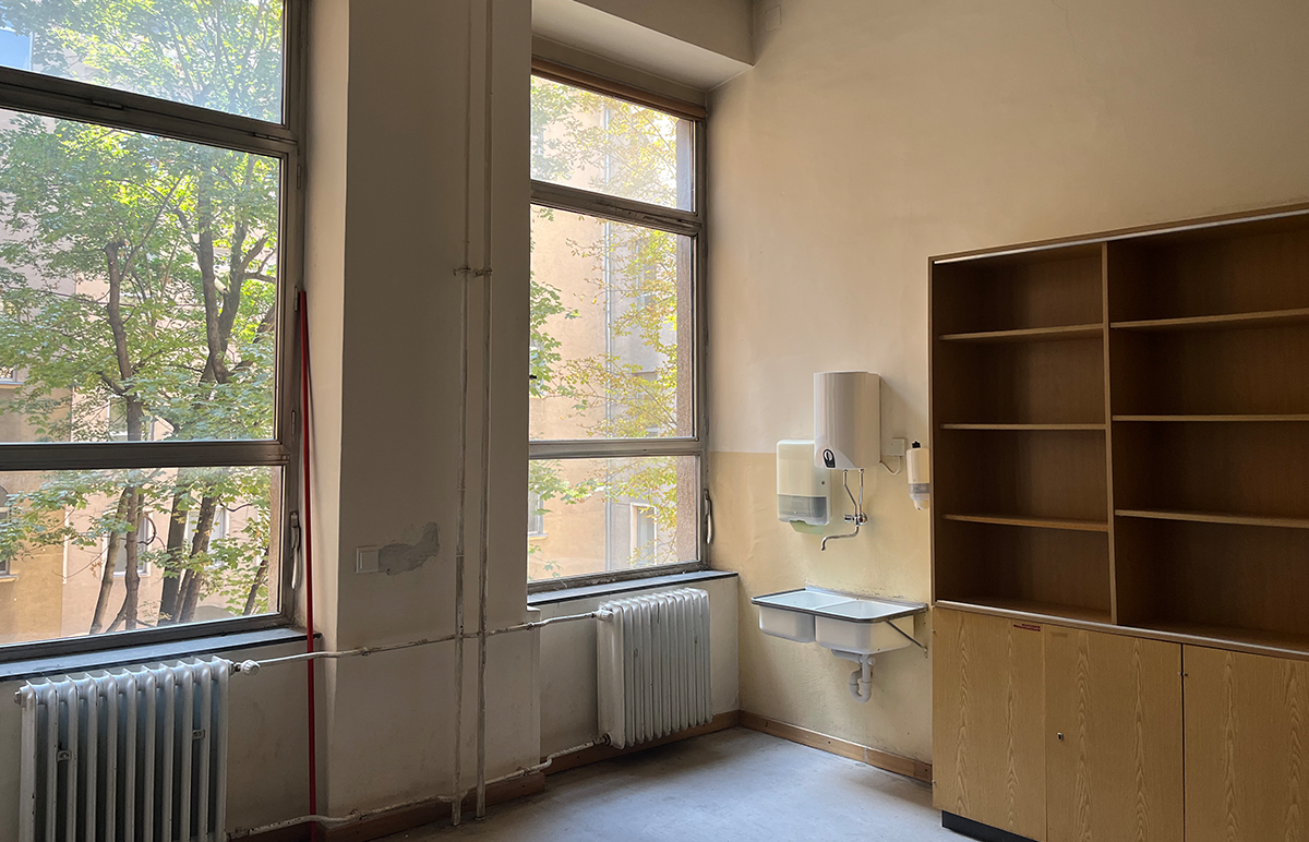 Raum mit zwei Fenstern auf der linken Seite, einem Waschbecken und einem leeren Regal