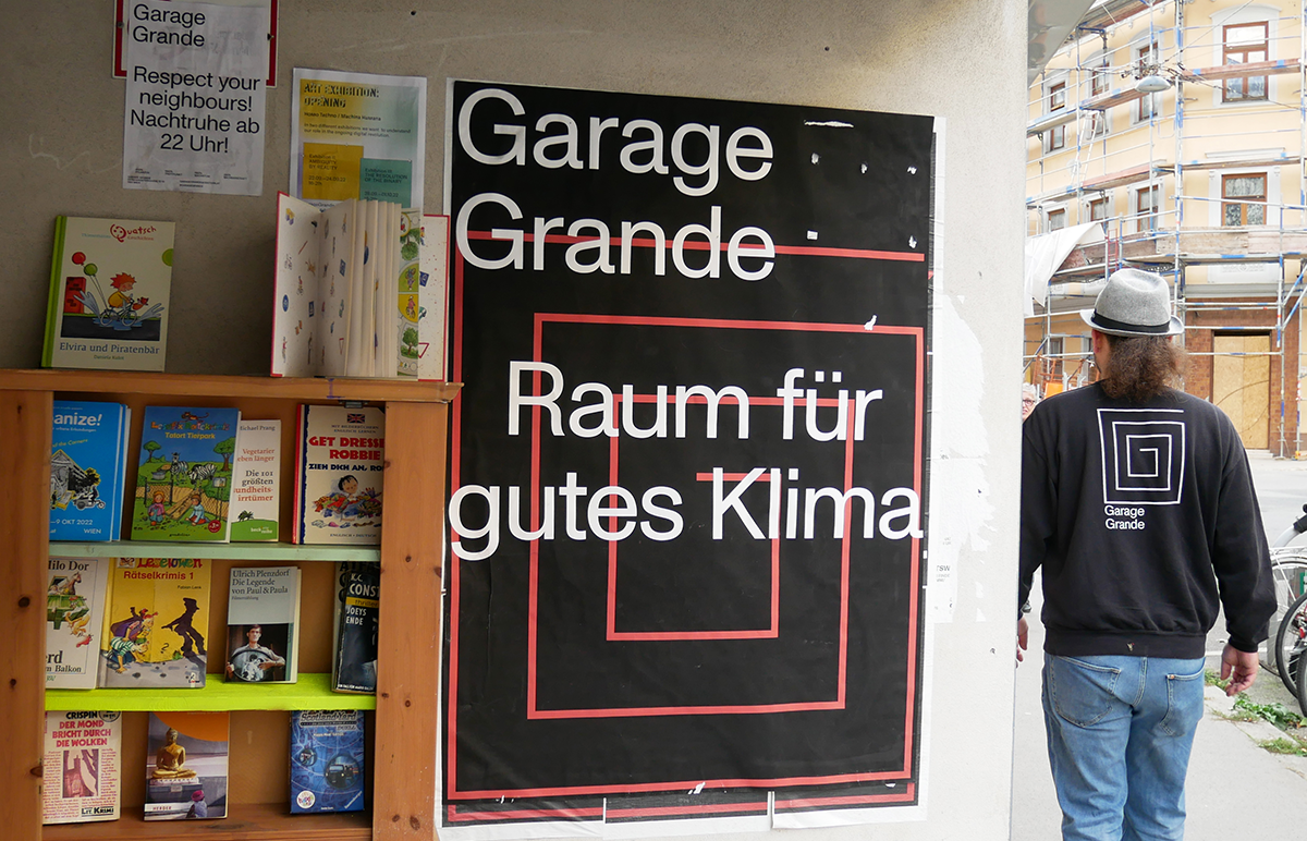 Plakat der Garage Grande mit dem Motto: Raum für gutes Klima. Daneben das offene Bücherregal