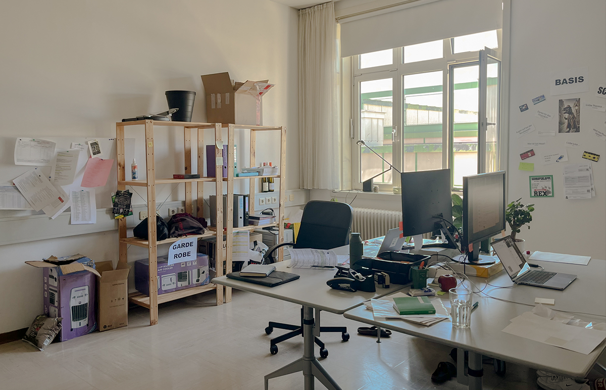 schräger Blick in eines der mittelgroßen Ateliers, mit zwei PC Arbeitsplätzen und Holzregalen an den Wänden.