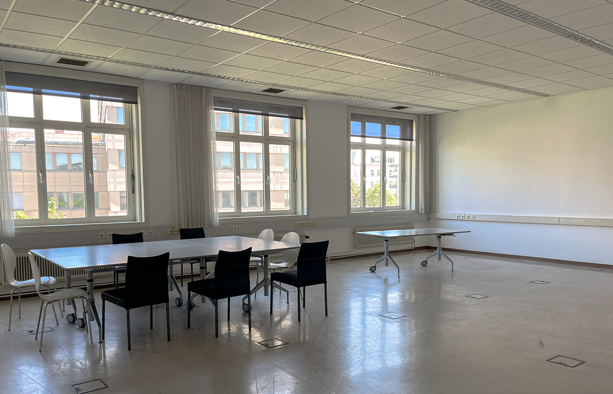 Blick auf drei zu einer Gruppe zusammengestellte Tische in einen der größeren Räume in der Zwischennutzung.