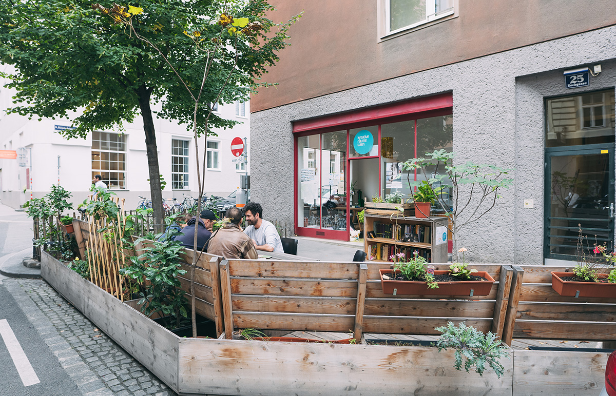 Mehrere Menschen sitzen auf dem Parklet vor dem Büro von Kreative Räume Wien