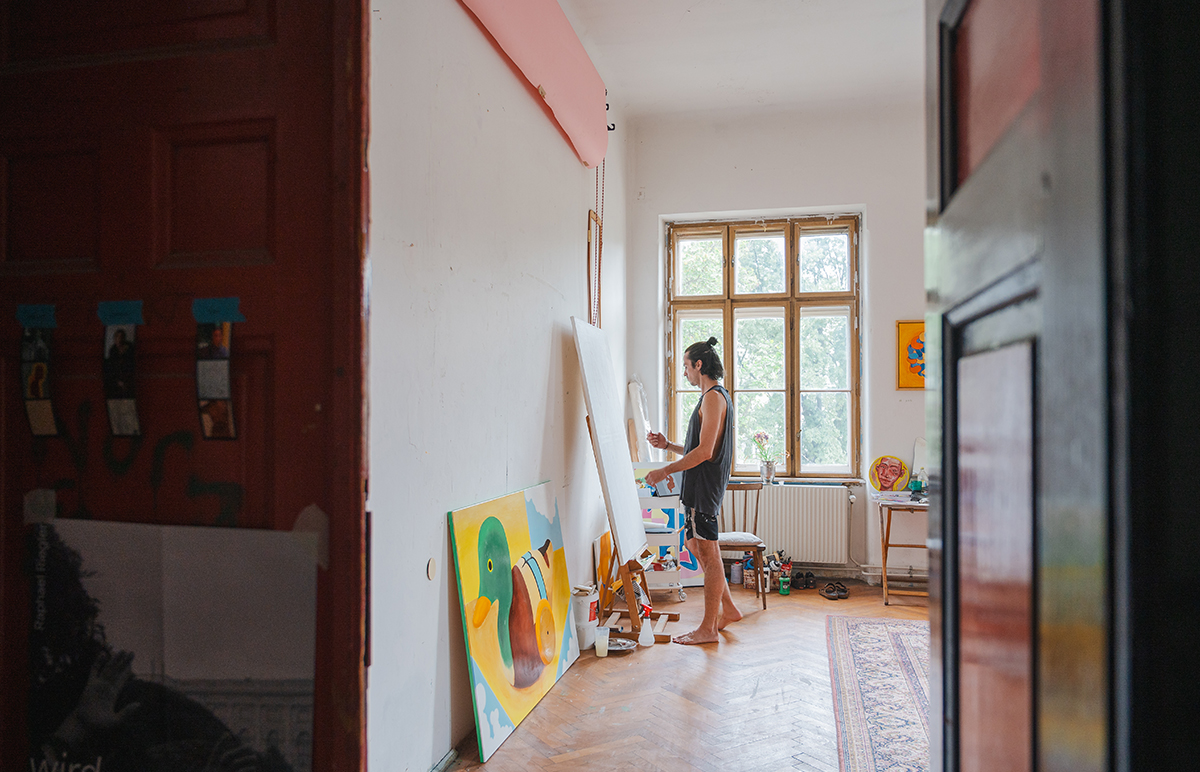 Blick in ein Atelier mit einer Person, die malt.